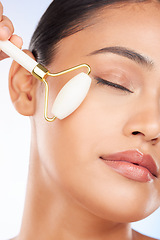Image showing Woman, face roller and massage in studio for skincare, grooming and aesthetic dermatology on white background. Model, crystal cosmetics and facial beauty tools for lymphatic drainage, shine and glow