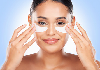 Image showing Skincare, portrait and woman with eye mask for anti aging luxury skin glow on blue background. Cosmetics, facial detox and face of happy model with solution or collagen pad for dermatology in studio.