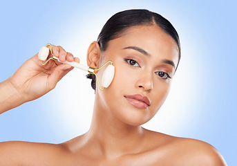 Image showing Woman, face and roller, beauty and skincare with tools, stone and natural cosmetics on blue background. Facial massage, portrait and skin glow, crystal and equipment with dermatology in a studio