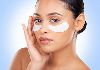 Image showing Portrait, skincare and eye mask with a natural woman in studio on a blue background for antiaging treatment. Face, beauty and wellness product with a young model at the salon for a facial application