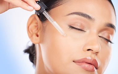 Image showing Essential oil, facial and woman in studio for skincare, wellness or hydration serum application on blue background. Hyaluronic acid, vitamin c or retinol for lady face, collagen or cosmetic treatment