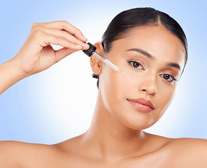 Image showing Skincare, portrait and woman in studio with oil for beauty, wellness or serum application on blue background. Hyaluronic acid, vitamin c or retinol facial for female face, mask or cosmetic treatment