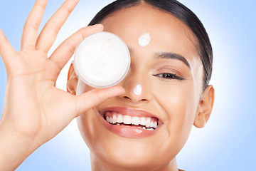 Image showing Portrait, happy woman and cream container for face, aesthetic skincare and shine on blue background. Young model, facial beauty and moisturizer jar for sunscreen, cosmetics and dermatology in studio