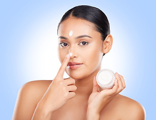 Image showing Portrait, woman and face cream container in studio for aesthetic skincare, shine and promo on blue background . Model, facial beauty and moisturizer jar of sunscreen, dermatology or cosmetics on nose