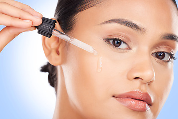 Image showing Woman, portrait and oil serum for beauty, cosmetics and skincare product on a blue background. Young person with facial liquid, dermatology dropper or collagen for skin care makeup on face in studio