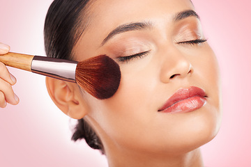 Image showing Beauty, cosmetics and woman in a studio with a brush for face foundation or glamour routine. Makeup, self care and closeup of young female model with cosmetology product isolated by pink background.