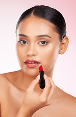 Image showing Portrait, beauty and makeup with a woman closeup on a pink background in studio for luxury cosmetics. Aesthetic, lipstick or product with a young model getting ready to apply red lipgloss to her face