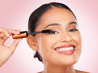 Image showing Portrait, makeup and a woman with mascara on a pink background for eyelash beauty in studio. Smile, young and a female model marketing a cosmetics product for facial glow, skincare or wellness