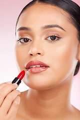 Image showing Portrait, beauty and lipstick with a woman closeup on a pink background in studio for luxury cosmetics. Aesthetic, makeup or product with a young model getting ready to apply red lipgloss to her face