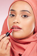 Image showing Portrait, beauty and lipstick with a muslim woman closeup in studio on a pink background for cosmetics. Face, makeup and islamic with a young model in an hijab to apply a product for red color