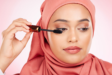 Image showing Beauty, makeup and mascara with a muslim woman closeup in studio on a pink background for cosmetics. Luxury, eyelash and brush with a young islamic model getting ready to apply cosmetics to her face