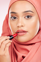 Image showing Portrait, beauty and makeup with a muslim woman closeup in studio on a pink background for cosmetics. Face, lipstick and islamic with a young model in an hijab to apply a product for red color