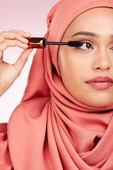 Image showing Beauty, luxury and mascara with a muslim woman closeup in studio on a pink background for cosmetics. Makeup, eyelash and brush with a young islamic model getting ready to apply cosmetics to her face