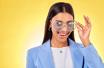 Image showing Funny, woman and sunglasses with tongue out, comedy and silly face in a studio. Yellow background, crazy and young female person with modern fashion, trendy cool style and creative work clothing