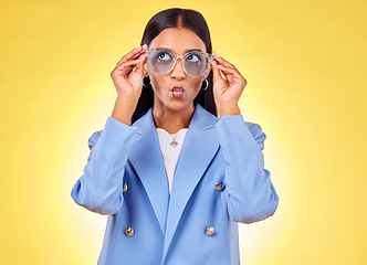 Image showing Funny, happy woman and sunglasses with kiss, comedy and silly face in a studio. Yellow background, pout and young female person with modern fashion, trendy cool style and creative work clothing