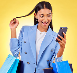 Image showing Shopping, phone and woman with surprise as customer happy for retail fashion isolated in studio yellow background. Shocked, online and young person with discount, deal and promo on clothes or product