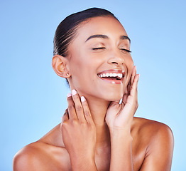 Image showing Skincare, beauty and face of happy woman in studio with blue background and dermatology or cosmetics for healthy glow. Indian, model and happiness with hands on natural skin, facial or self care