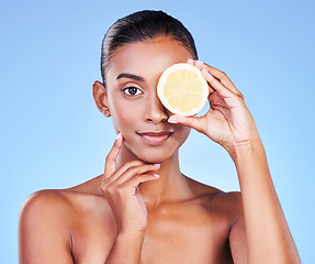Image showing Portrait, woman and lemon on eyes in studio for vitamin c cosmetics, eco friendly beauty or detox. Face of indian model, healthy skincare or citrus fruit of sustainable dermatology on blue background