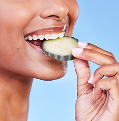 Image showing Woman, mouth and bite on cucumber in diet, natural nutrition or detox against a blue studio background. Closeup of female person eating organic vegetable in healthy wellness, dermatology or beauty