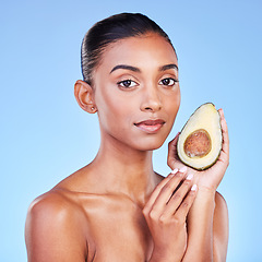 Image showing Avocado, beauty and portrait of woman in studio for cosmetics, nutrition and diet on blue background. Indian model, skincare and fruit for sustainable dermatology, vegan wellness and facial benefits