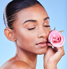 Image showing Rose, face and skincare of woman in studio for eco cosmetics, natural wellness or blue background. Indian model, flowers and eyes closed for vegan beauty, sustainable dermatology and floral aesthetic