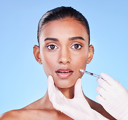 Image showing Surprise, woman face and plastic surgery, beauty and injection in portrait, doctor hands on blue background. Cosmetic treatment, wow and liquid collagen in needle syringe with skincare in a studio