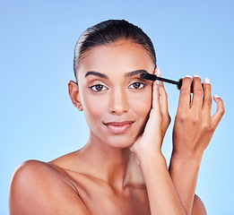 Image showing Woman, mascara and makeup, portrait and brush with transformation and beauty product on blue background. Eyelash extension, cosmetology and cosmetics with Indian model, volume and change in a studio