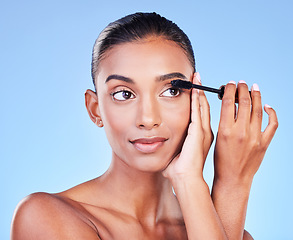 Image showing Woman, mascara and makeup, beauty and brush with transformation and cosmetic product on blue background. Eyelash extension, cosmetology and volume with Indian model, wellness and change in a studio