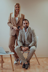 Image showing A business couple posing for a photograph together against a beige backdrop, capturing their professional partnership and creating a timeless image of unity and success.