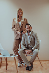 Image showing A business couple posing for a photograph together against a beige backdrop, capturing their professional partnership and creating a timeless image of unity and success.