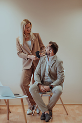 Image showing A business couple posing for a photograph together against a beige backdrop, capturing their professional partnership and creating a timeless image of unity and success.