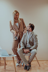 Image showing A business couple posing for a photograph together against a beige backdrop, capturing their professional partnership and creating a timeless image of unity and success.