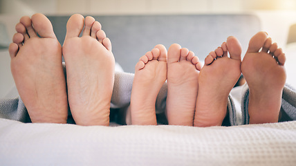 Image showing Family feet, bed and closeup with kid to relax with love, rest and sleeping on hotel mattress for vacation. Parents, sleep and bedroom with child, mom and father for bonding, care and safe in house