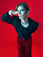 Image showing Gay, man and portrait with fashion, beauty and peace sign on studio red background with unique aesthetic with makeup. Lgbt, style and model with hand in photography, grunge or retro clothing