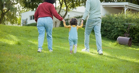 Image showing Family, walking and parents support a child in a backyard bonding by a home or house for care or love for a holiday. Outdoor, mother and father enjoying quality time and playing with kid in back view