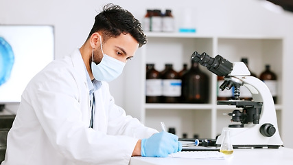 Image showing Scientist and research or medical engineer doing experiments to create a cure in a lab while wearing a mask. Healthcare professional working with science equipment and writing notes in a laboratory