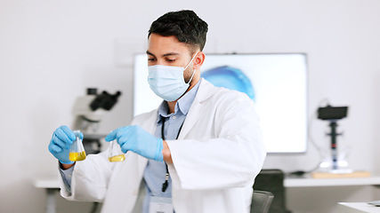 Image showing Scientist and research or medical engineer doing experiments to create a cure in a lab while wearing a mask. Healthcare professional working with science equipment and writing notes in a laboratory