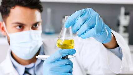 Image showing A thinking young scientist doing research to create a covid cure in a lab. Medical professional using science equipment in a laboratory. A serious male healthcare worker working with a mask.