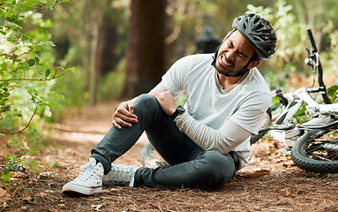 Image showing Man, knee pain and injury in forest with bike, stress and sitting on ground with emergency in nature. Cycling athlete, young guy and accident with bicycle, training and exercise with crash in woods