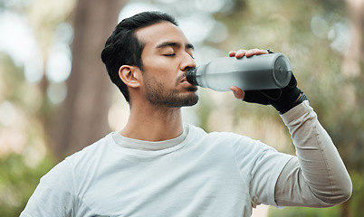 Image showing Sports, man and drinking water in park for exercise break, energy and workout rest. Thirsty athlete, asian runner and bottle for hydration, nutrition and healthy recovery of fitness in nature outdoor