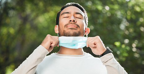 Image showing Covid, Asian man and take off mask for end of pandemic, breathing and outdoor protected. Corona, healthy guy and Japanese person remove face cover for fresh air, freedom and decrease infection rates