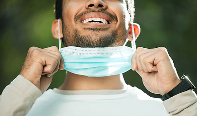 Image showing Mouth, mask and remove with a man breathing fresh air in nature, feeling happy at the end of restrictions. Covid, freedom and post lockdown with a person closeup in the forest, woods or wilderness