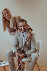 Image showing A business couple posing for a photograph together against a beige backdrop, capturing their professional partnership and creating a timeless image of unity and success.