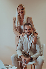 Image showing A business couple posing for a photograph together against a beige backdrop, capturing their professional partnership and creating a timeless image of unity and success.