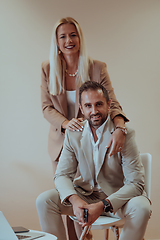 Image showing A business couple posing for a photograph together against a beige backdrop, capturing their professional partnership and creating a timeless image of unity and success.