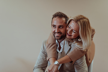 Image showing A business couple posing for a photograph together against a beige backdrop, capturing their professional partnership and creating a timeless image of unity and success.