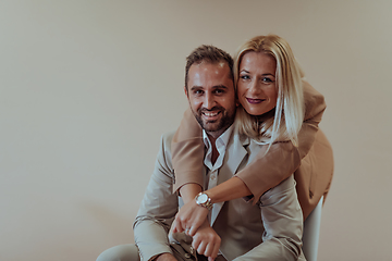 Image showing A business couple posing for a photograph together against a beige backdrop, capturing their professional partnership and creating a timeless image of unity and success.