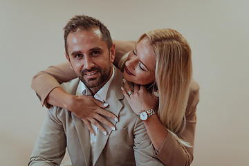 Image showing A business couple posing for a photograph together against a beige backdrop, capturing their professional partnership and creating a timeless image of unity and success.