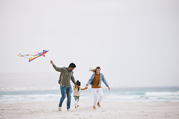 Image showing Family, running and flying a kite at beach outdoor with fun energy, happiness and love in nature. Man and woman playing with a girl kid on holiday, freedom adventure or vacation at sea with banner