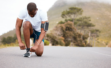 Image showing Fitness, tie or runner with shoes on a road by nature for exercise, training or outdoor workout. Sports race, black man or healthy athlete on street with footwear or headphones for streaming music